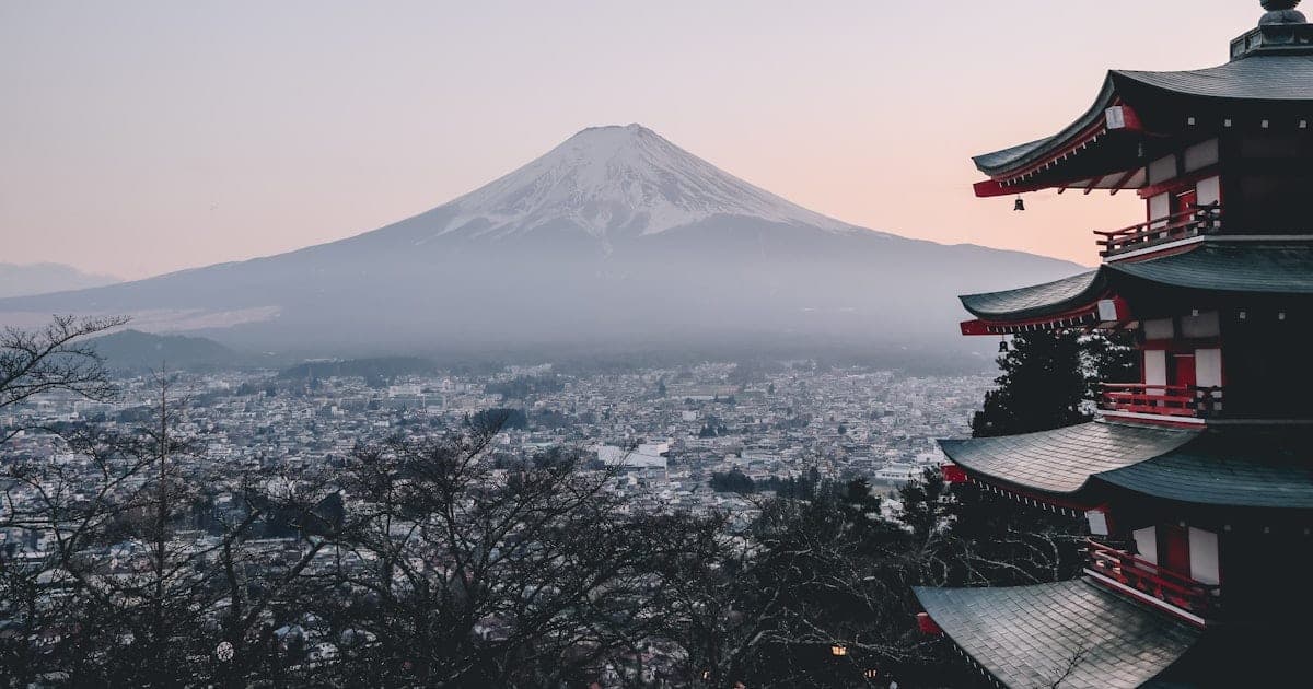 A bullet train passing cherry blossoms with a temple and Mount Fuji in the background in Japan