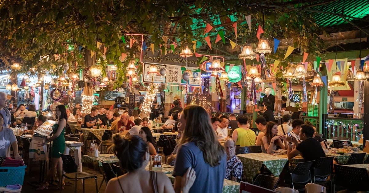 A colorful Thai street-food market stall with noodle dishes and fresh fruit shakes